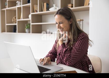 Femme heureuse travaillant sur ordinateur dans le bureau à domicile Banque D'Images
