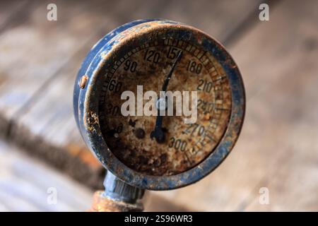 Un vieux manomètre rouillé avec une face noire et un fond blanc. Les chiffres sur la jauge sont délavés et difficiles à lire Banque D'Images