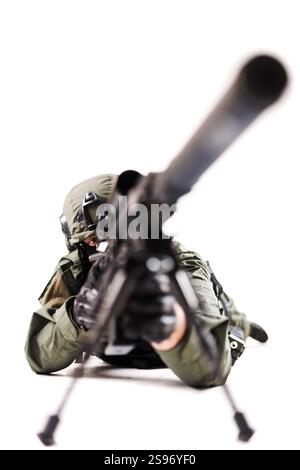 Gros plan d'un soldat tactique habillé en camouflage, couché sur le ventre et visant avec un fusil. L'arrière-plan est blanc, soulignant la mise au point intense et Banque D'Images