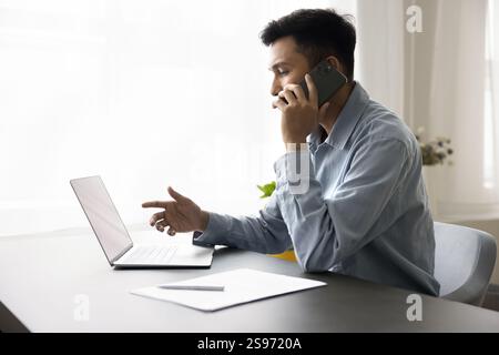 Un jeune employé confiant passe un appel téléphonique professionnel sur le lieu de travail Banque D'Images