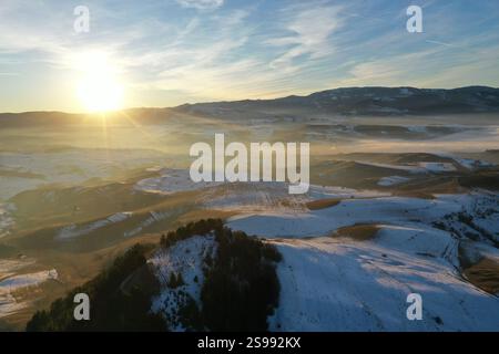 Vue aérienne du coucher de soleil sur les montagnes brumeuses d'hiver par drone Banque D'Images