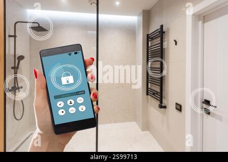 Young woman holding smart phone avec l'application de sécurité lancé à la maison. Concept de contrôle et la gestion de la sécurité à la maison à partir d'un terminal mobile Banque D'Images