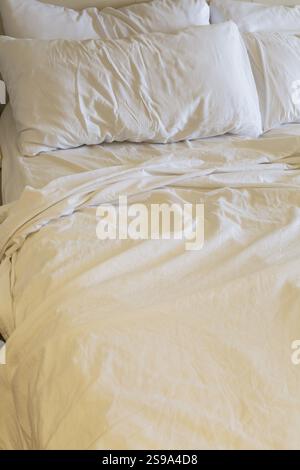Gros plan de draps et oreillers en coton blanc ondulés et froissés sur un lit king size non fait, la Spezia, Italie, Europe Banque D'Images