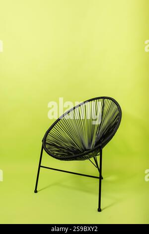 chaise en métal noir en rotin artificiel fond vert clair. meubles sur un fond de papier Banque D'Images