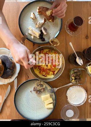Table de petit déjeuner turc. Pose à plat des mains des peuples prenant des pâtisseries, des légumes, des légumes verts, des olives, des fromages, oeufs frits, épices, confitures, miel, thé au coppe Banque D'Images