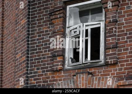 Un fragment d'un mur de briques et une fenêtre cassée d'une vieille maison abandonnée. Banque D'Images