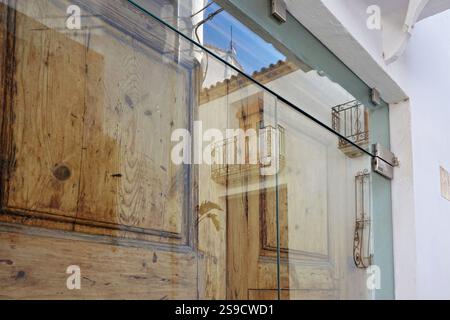 Porte vitrée avec des reflets des bâtiments de la vieille ville d'Altea. Petite ville pittoresque d'Altea avec des rues étroites et des maisons blanchies à la chaux près de la Méditerranée Banque D'Images