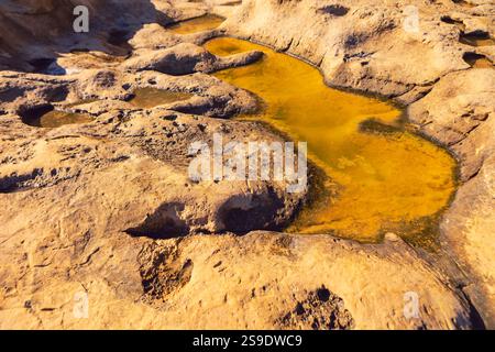 Formations rocheuses naturelles avec des bassins d'eau peu profonds qui ont une teinte jaunâtre, indiquant la présence de marais salants. Les saladiers mettent en évidence le processus de Banque D'Images