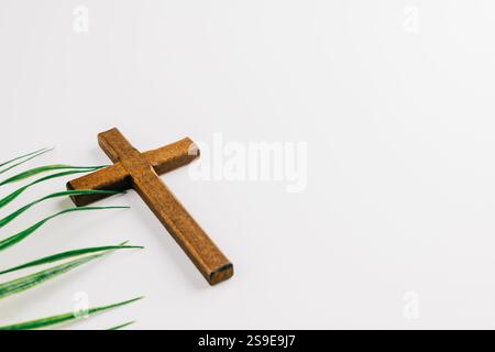 Concept Palm Sunday avec croix en bois et frondes de palmier vertes sur fond. Un symbole de foi et de célébration de Pâques, mettant en valeur les traditions et le meani Banque D'Images