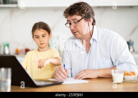 Père aide sa fille à faire ses devoirs à l'aide d'un ordinateur portable Banque D'Images