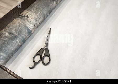 Couper le papier peint avant de le coller au mur, ciseaux, ruban à mesurer et crayon sur la table, couper le papier peint à la taille Banque D'Images