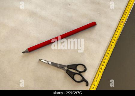 Couper le papier peint avant de le coller au mur, ciseaux, ruban à mesurer et crayon sur la table, couper le papier peint à la taille Banque D'Images