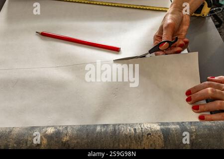 Couper le papier peint avant de le coller au mur, ciseaux, ruban à mesurer et crayon sur la table, couper le papier peint à la taille Banque D'Images