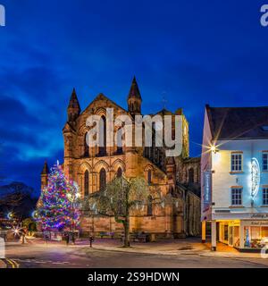 Vue extérieure de l'abbaye de Hexham illuminée la nuit à Noël avec un arbre de Noël éclairé et décoré à Hexham Town Square dans le Northumberland Banque D'Images