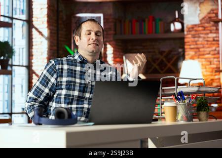 Travailleur souriant au bureau à domicile se sentant fier après avoir vu qu'il a atteint l'objectif de vente sur l'écran de l'ordinateur portable. Smug employé se réjouissant après avoir reçu une promotion au travail, lisant l'e-mail sur ordinateur portable Banque D'Images