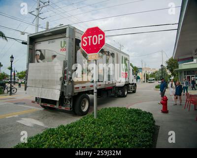 Vue large US Foods semi-camion livraison en passant un panneau d'arrêt dans la rue. Plantes vertes devant et bouche d'incendie rouge sur la droite près des chaises et int Banque D'Images