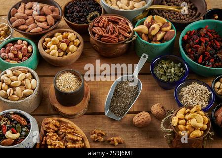 Mélange de noix dans des bols différents sur une table en bois. Noix, arachides, noix de pécan, amandes, noix de cajou, pistache, abricot, raisins secs, dattes, noix de coco Banque D'Images