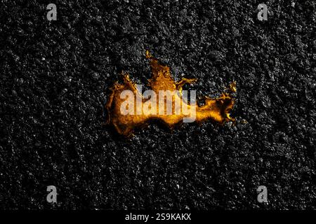 Déversement de liquide doré sur une surface d'asphalte foncé Banque D'Images