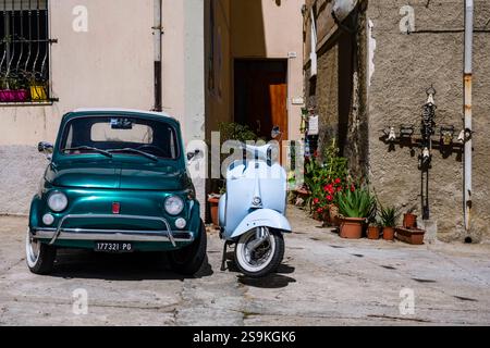 Deux véhicules historiques, une Fiat 500 vert foncé et un scooter Vespa bleu clair, sont garés dans une rue de la petite ville de Bitti. Bitti Sardaigne Italie F Banque D'Images