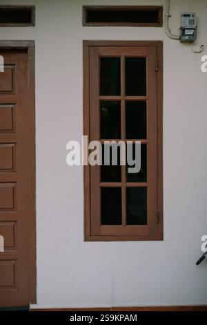 Simple cadre de fenêtre marron sur un mur blanc. Banque D'Images