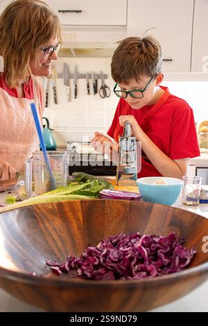 Mère et fils préparant des légumes ensemble dans une cuisine Banque D'Images