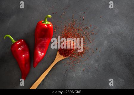 Poivrons Capia frais et flocons de piment ou poudre dans une cuillère en bois sur table rustique grise, épices turques saines Banque D'Images