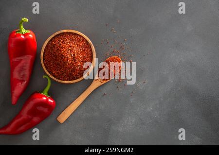 Poivrons Capia frais et flocons de piment ou poudre dans une cuillère en bois sur table rustique grise, épices turques saines Banque D'Images