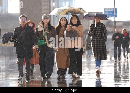 Les gens s'abritent de la pluie sous un parapluie alors qu'ils traversent le London Bridge dans le centre de Londres. Les tempêtes provoquent des inondations et des perturbations accrues dans les transports à travers de grandes parties de l'Angleterre et du pays de Galles. Date de la photo : lundi 27 janvier 2025. Banque D'Images