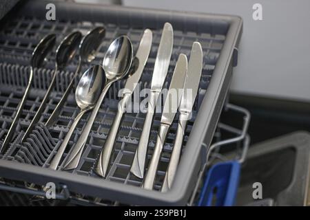 Couverts argentés soigneusement disposés dans un bac de lave-vaisselle Banque D'Images