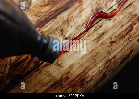 Gros plan de l'époxy rouge appliqué sur du bois à la texture altérée Banque D'Images