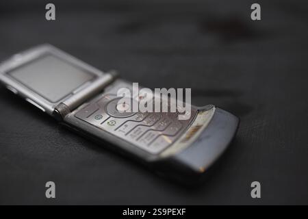 Vue latérale d'un téléphone à rabat Motorola sur une surface noire, montrant les détails du clavier Motorola RAZR V3 Banque D'Images