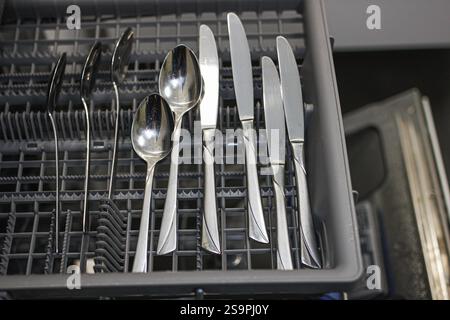 Couteaux et cuillères rangés dans un bac à couverts de lave-vaisselle Banque D'Images