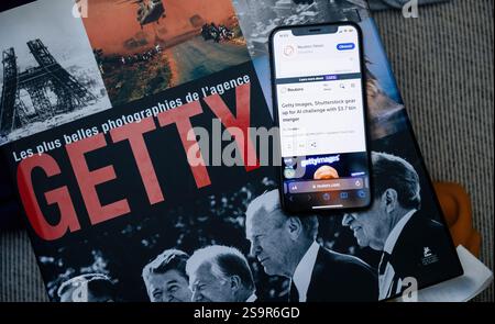 Paris, France - 1er janvier 2025 : un smartphone affichant un article Reuters sur la fusion de Getty images et Shutterstock, placé sur un livre photo Getty Banque D'Images