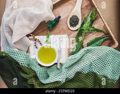 Сomposition avec tisane, vieux livre, feuilles de pissenlit et une bouteille d'essence à base de plantes. Concept de plantes médicinales. Banque D'Images