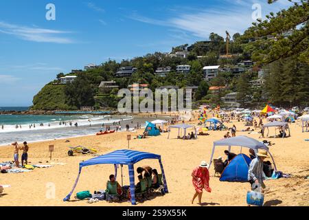 Les vacanciers se détendent un jour d'été en Australie, beaucoup sous une cabane pour fournir une protection solaire à Palm Beach à Sydney, Nouvelle-Galles du Sud, Australie, 2025 Banque D'Images