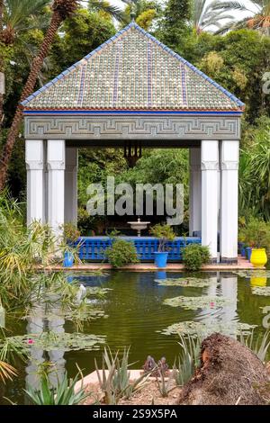 Marrakech, Maroc. Toit de tuiles marocaines au sommet d'un belvédère et d'un étang tranquille. Banque D'Images