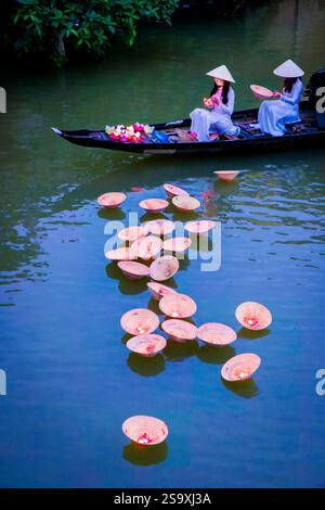Vietnam, Hue. Placement traditionnel de lanternes allumées dans la rivière dans le cadre de la célébration du nouvel an. Interprété par deux femmes en Ao traditionnel Banque D'Images