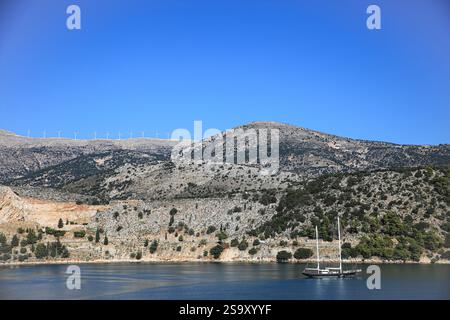 Grèce. Un voilier passe devant une île méditerranéenne grecque avec des éoliennes Banque D'Images