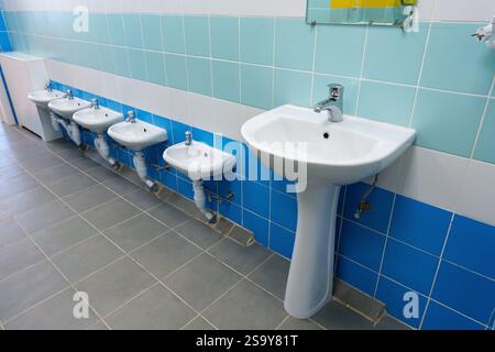 Toilettes propres et modernes avec plusieurs éviers et urinoirs dans un établissement bien entretenu Banque D'Images