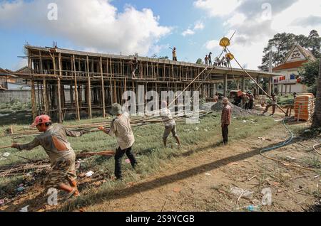 Srey Santhor, Cambodge. 28 janvier 2025 : des travailleurs khmers sans équipement de sécurité construisent un bâtiment sur des pieux (école/but religieux) sur une pagode, près du fleuve Mékong. L'industrie de la construction cambodgienne en plein essor emploie environ 250 000 travailleurs, dont beaucoup ne sont pas qualifiés ou travaillent de manière informelle comme journaliers. Les accidents et les problèmes de santé sont fréquents pour la main-d'œuvre dans le secteur, beaucoup ont encore peu de connaissances sur les soins de santé et les prestations d'assurance accident auxquelles ils ont droit par le biais du Fonds national de sécurité sociale (NSSF) géré par le gouvernement. Crédit : Kevin Izorce/Alamy Live News Banque D'Images