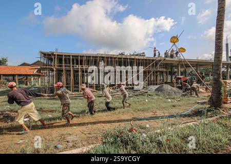 Srey Santhor, Cambodge. 28 janvier 2025 : des travailleurs khmers sans équipement de sécurité construisent un bâtiment sur des pieux (école/but religieux) sur une pagode, près du fleuve Mékong. L'industrie de la construction cambodgienne en plein essor emploie environ 250 000 travailleurs, dont beaucoup ne sont pas qualifiés ou travaillent de manière informelle comme journaliers. Les accidents et les problèmes de santé sont fréquents pour la main-d'œuvre dans le secteur, beaucoup ont encore peu de connaissances sur les soins de santé et les prestations d'assurance accident auxquelles ils ont droit par le biais du Fonds national de sécurité sociale (NSSF) géré par le gouvernement. Crédit : Kevin Izorce/Alamy Live News Banque D'Images