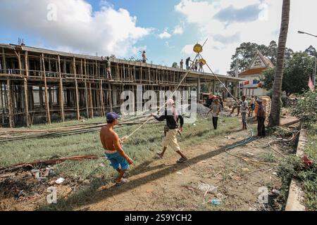 Srey Santhor, Cambodge. 28 janvier 2025 : des travailleurs khmers sans équipement de sécurité construisent un bâtiment sur des pieux (école/but religieux) sur une pagode, près du fleuve Mékong. L'industrie de la construction cambodgienne en plein essor emploie environ 250 000 travailleurs, dont beaucoup ne sont pas qualifiés ou travaillent de manière informelle comme journaliers. Les accidents et les problèmes de santé sont fréquents pour la main-d'œuvre dans le secteur, beaucoup ont encore peu de connaissances sur les soins de santé et les prestations d'assurance accident auxquelles ils ont droit par le biais du Fonds national de sécurité sociale (NSSF) géré par le gouvernement. Crédit : Kevin Izorce/Alamy Live News Banque D'Images