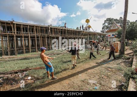 Srey Santhor, Cambodge. 28 janvier 2025 : des travailleurs khmers sans équipement de sécurité construisent un bâtiment sur des pieux (école/but religieux) sur une pagode, près du fleuve Mékong. L'industrie de la construction cambodgienne en plein essor emploie environ 250 000 travailleurs, dont beaucoup ne sont pas qualifiés ou travaillent de manière informelle comme journaliers. Les accidents et les problèmes de santé sont fréquents pour la main-d'œuvre dans le secteur, beaucoup ont encore peu de connaissances sur les soins de santé et les prestations d'assurance accident auxquelles ils ont droit par le biais du Fonds national de sécurité sociale (NSSF) géré par le gouvernement. Crédit : Kevin Izorce/Alamy Live News Banque D'Images