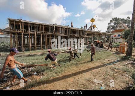 Srey Santhor, Cambodge. 28 janvier 2025 : des travailleurs khmers sans équipement de sécurité construisent un bâtiment sur des pieux (école/but religieux) sur une pagode, près du fleuve Mékong. L'industrie de la construction cambodgienne en plein essor emploie environ 250 000 travailleurs, dont beaucoup ne sont pas qualifiés ou travaillent de manière informelle comme journaliers. Les accidents et les problèmes de santé sont fréquents pour la main-d'œuvre dans le secteur, beaucoup ont encore peu de connaissances sur les soins de santé et les prestations d'assurance accident auxquelles ils ont droit par le biais du Fonds national de sécurité sociale (NSSF) géré par le gouvernement. Crédit : Kevin Izorce/Alamy Live News Banque D'Images