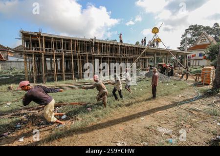 Srey Santhor, Cambodge. 28 janvier 2025 : des travailleurs khmers sans équipement de sécurité construisent un bâtiment sur des pieux (école/but religieux) sur une pagode, près du fleuve Mékong. L'industrie de la construction cambodgienne en plein essor emploie environ 250 000 travailleurs, dont beaucoup ne sont pas qualifiés ou travaillent de manière informelle comme journaliers. Les accidents et les problèmes de santé sont fréquents pour la main-d'œuvre dans le secteur, beaucoup ont encore peu de connaissances sur les soins de santé et les prestations d'assurance accident auxquelles ils ont droit par le biais du Fonds national de sécurité sociale (NSSF) géré par le gouvernement. Crédit : Kevin Izorce/Alamy Live News Banque D'Images