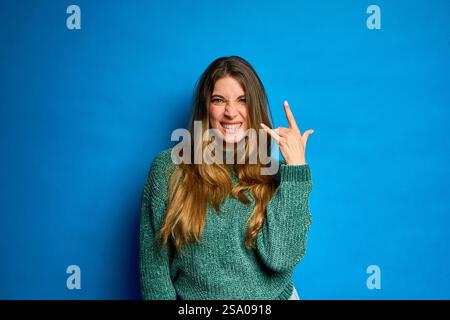Jeune femme rebelle montrant des gestes rock and roll de la main, exprimant sa passion pour la musique et le style de vie alternatif Banque D'Images