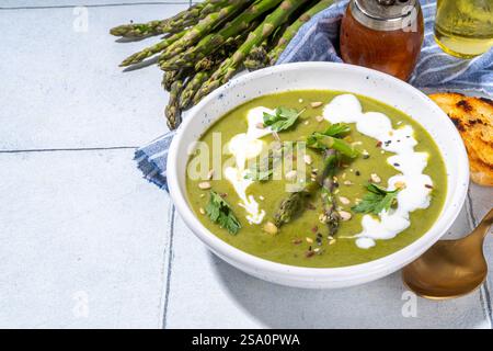 Soupe à la crème d'asperges vertes maison, crème aigre, décoration aux asperges fraîches et croûtons Banque D'Images