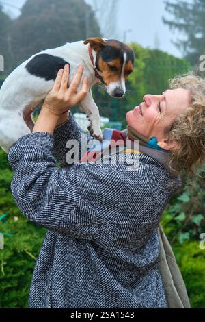 Heureuse femme âgée tenant son Jack russell terrier dans un jardin Banque D'Images