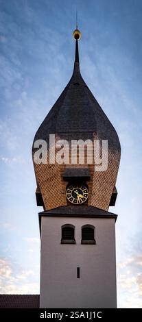 Une grande tour d'église avec un toit pointu distinctif, avec un cadran d'horloge et deux petites fenêtres. La tour est placée sur une toile de fond d'un ciel bleu w Banque D'Images