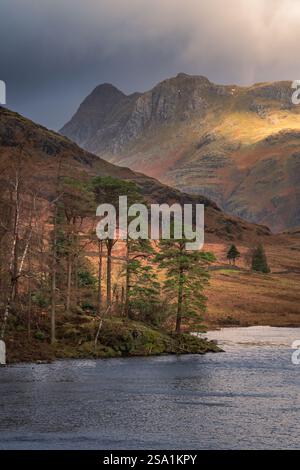 Lumière du soleil éclatant de nuages sombres sur les montagnes Langdale Pikes vues de Blea Tarn dans le Lake District anglais, Royaume-Uni. Banque D'Images